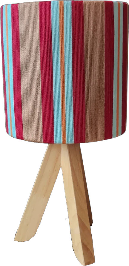 A table lamp wrapped in crimson, turquoise and tan yarn on a wooden tripod base