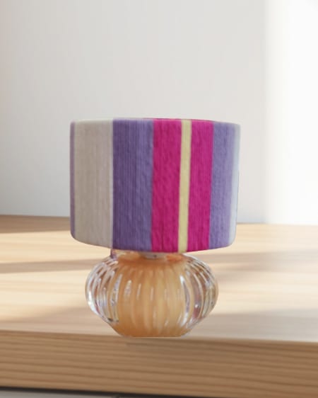 A small purple and magenta lamp on a glass base