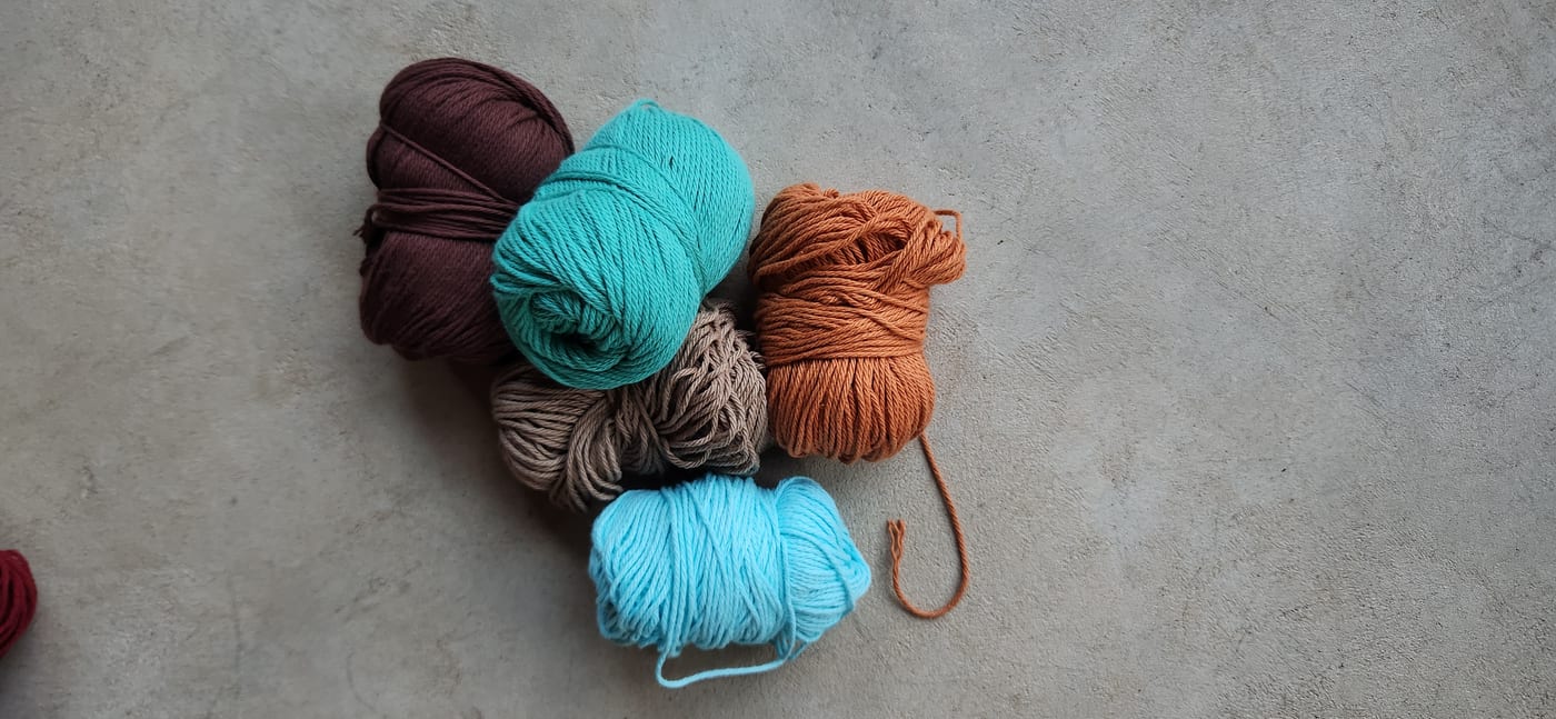 Balls of yarn in rust, teal, brown and sand